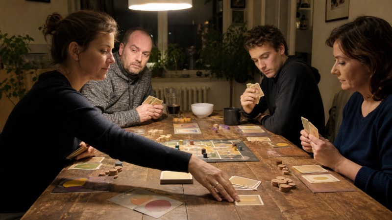 Hráč s pokerovou tváří drží karty těsně u sebe u herního stolu s žetony